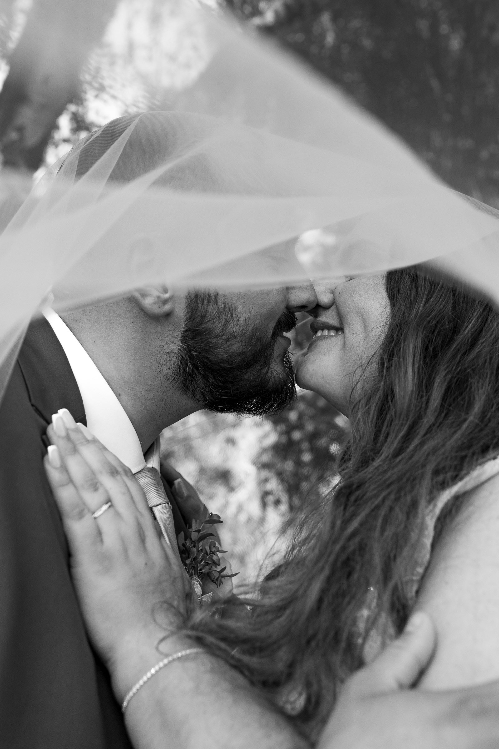 Mariés s’embrassant sous le voile de la mariée pendant leur séance couple